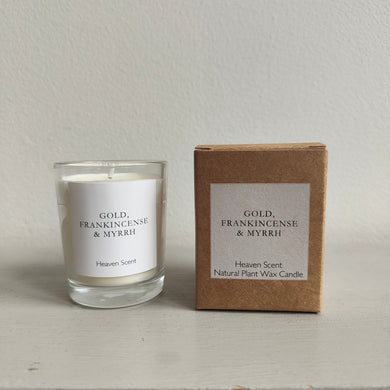 Candle labeled 'Gold, Frankincense & Myrrh' by Heaven Scent next to its packaging on a neutral background