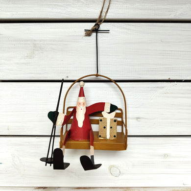 Decorative ornament of a Santa Claus figure on a ski lift against a wooden background by Shoeless Joe