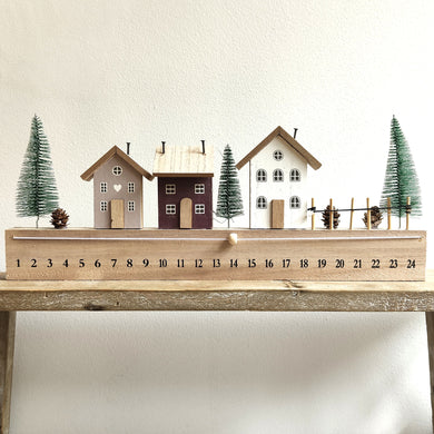 Decorative wooden advent calendar with houses and trees on a white background by Heaven Sends