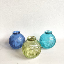 Three textured glass vases in blue, green, and turquoise on a white background